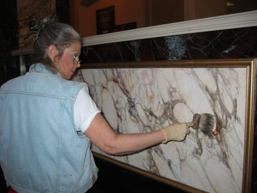 A woman is painting on the wall of a room.