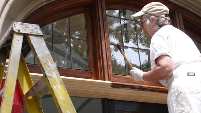 A man painting the inside of a window.