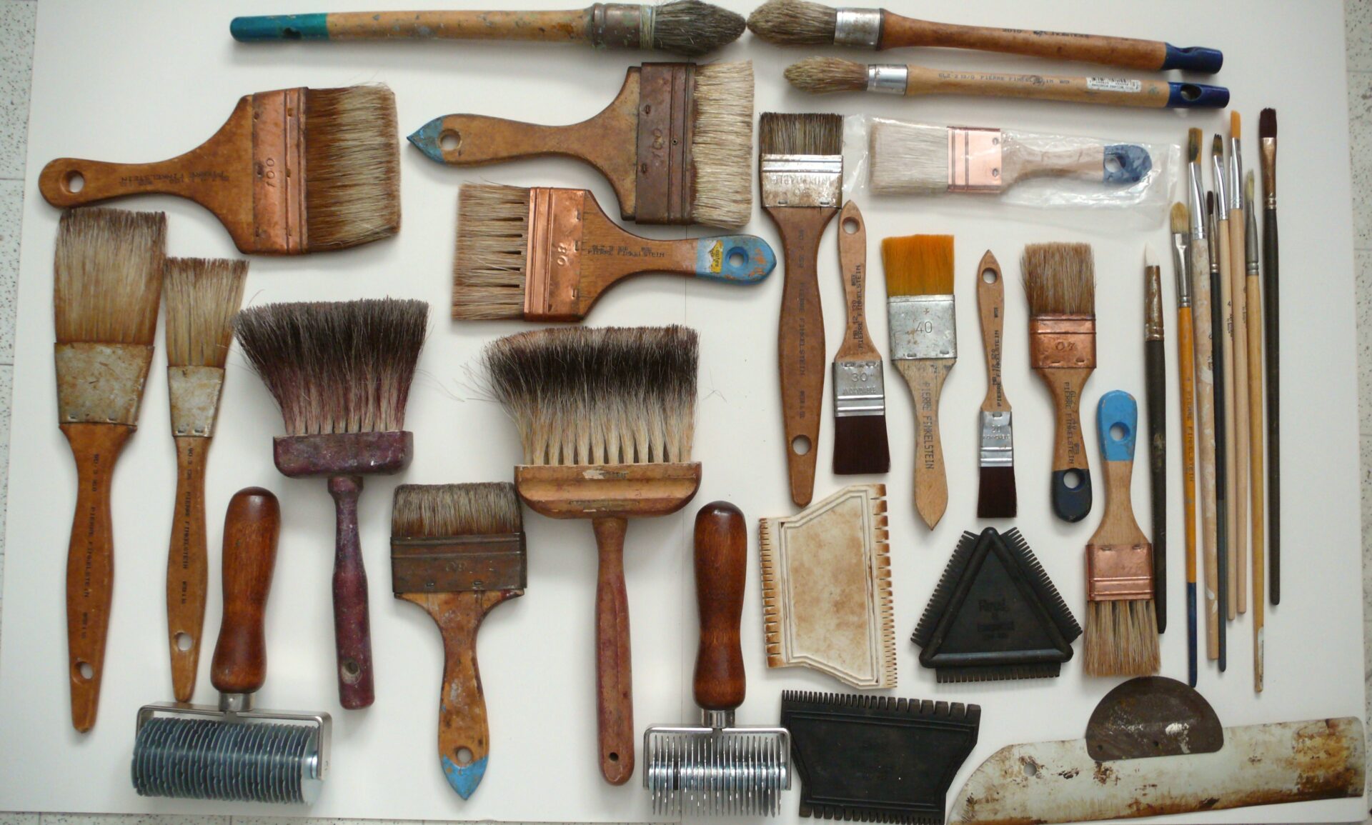 A bunch of different brushes and paint rollers