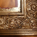 A close up of the ornate frame on a mirror.